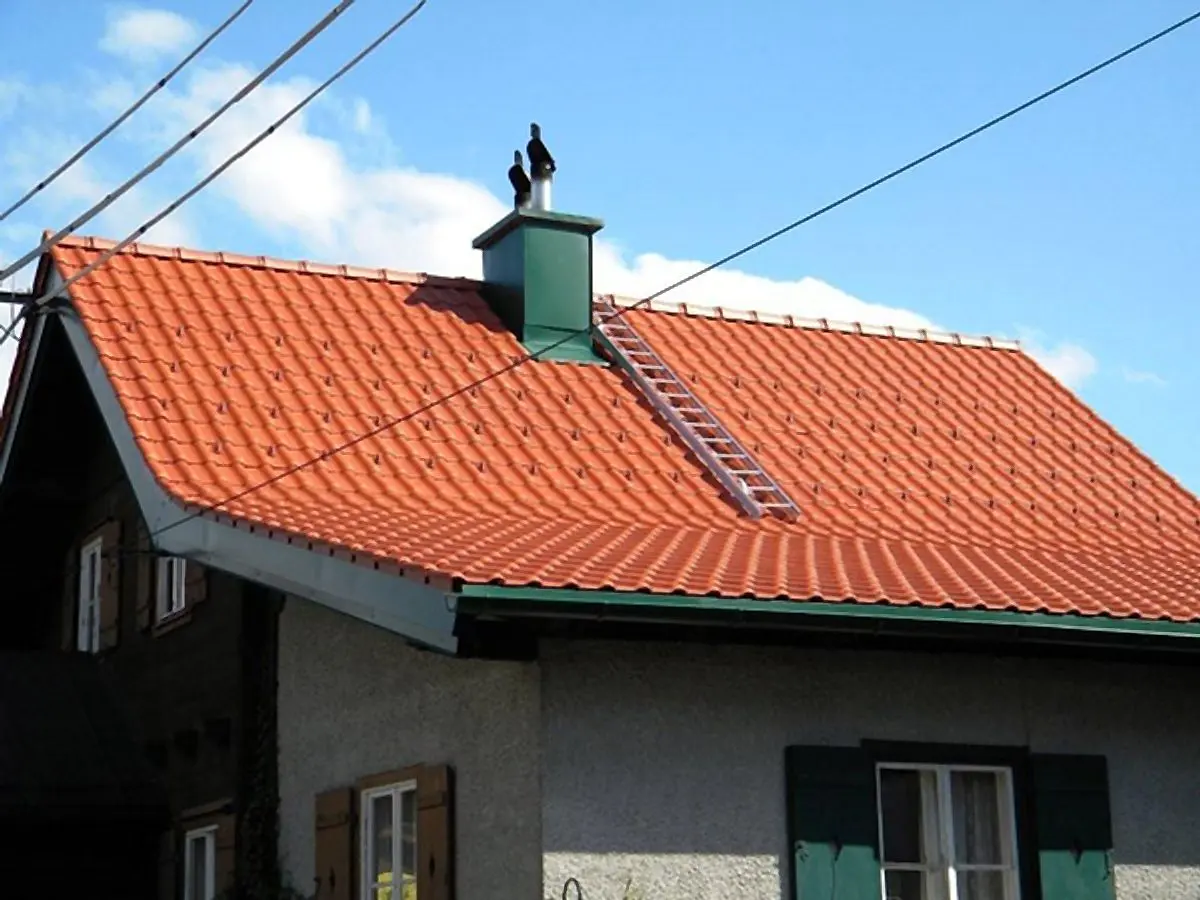 Ziegelrotes Dach mit Kamin und Leiter