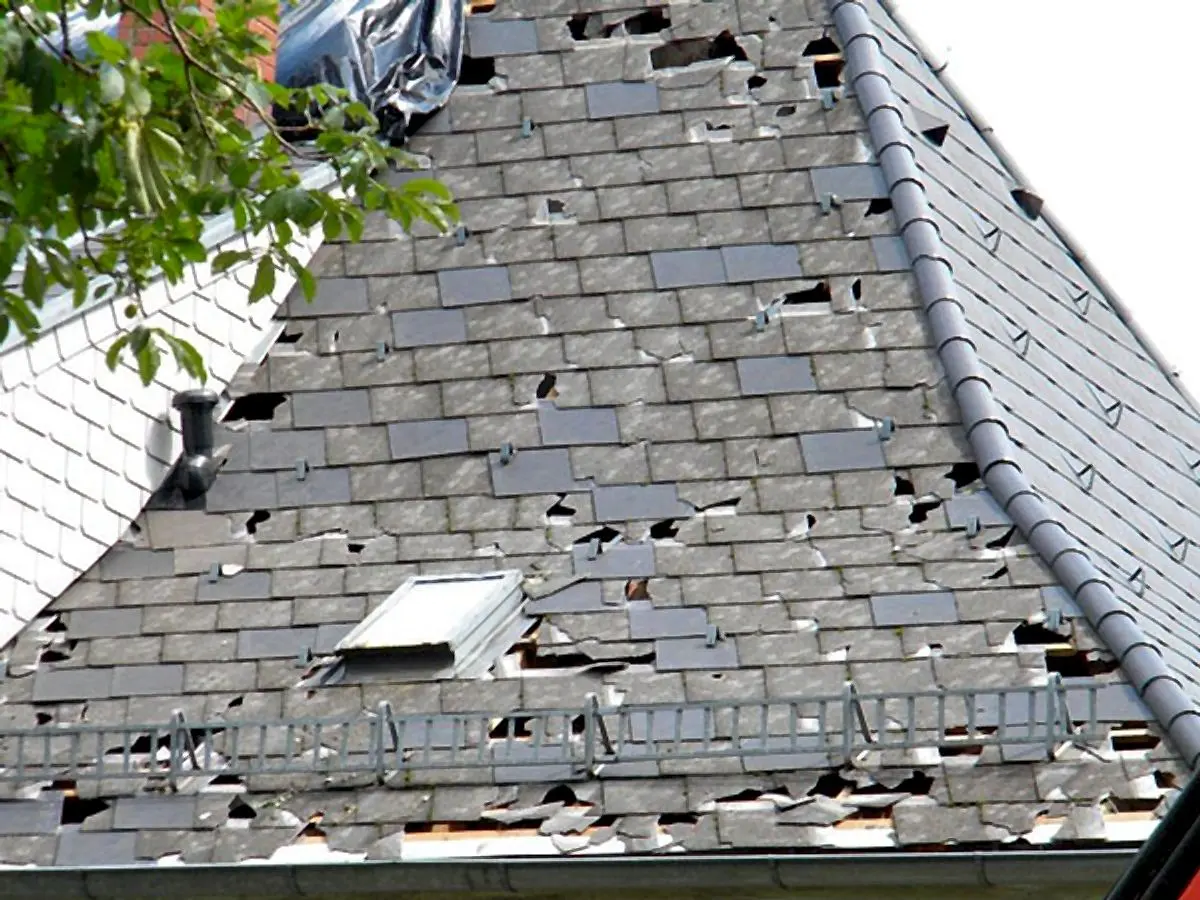Hagelschäden an einer Schieferdeckung mit Dachfenster
