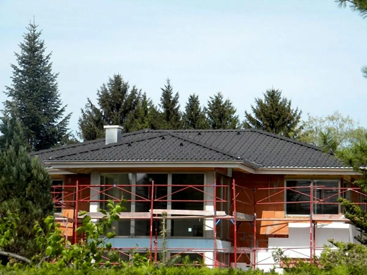 Dunkles Walmdach über einem Haus mit Gerüst